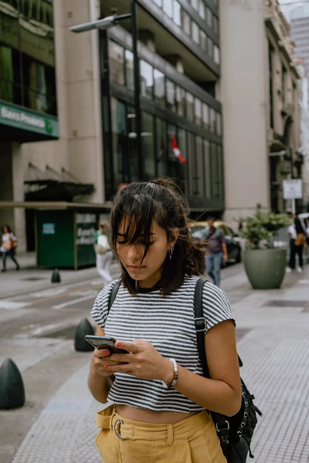 Traveller checking a booking on her phone on a city street